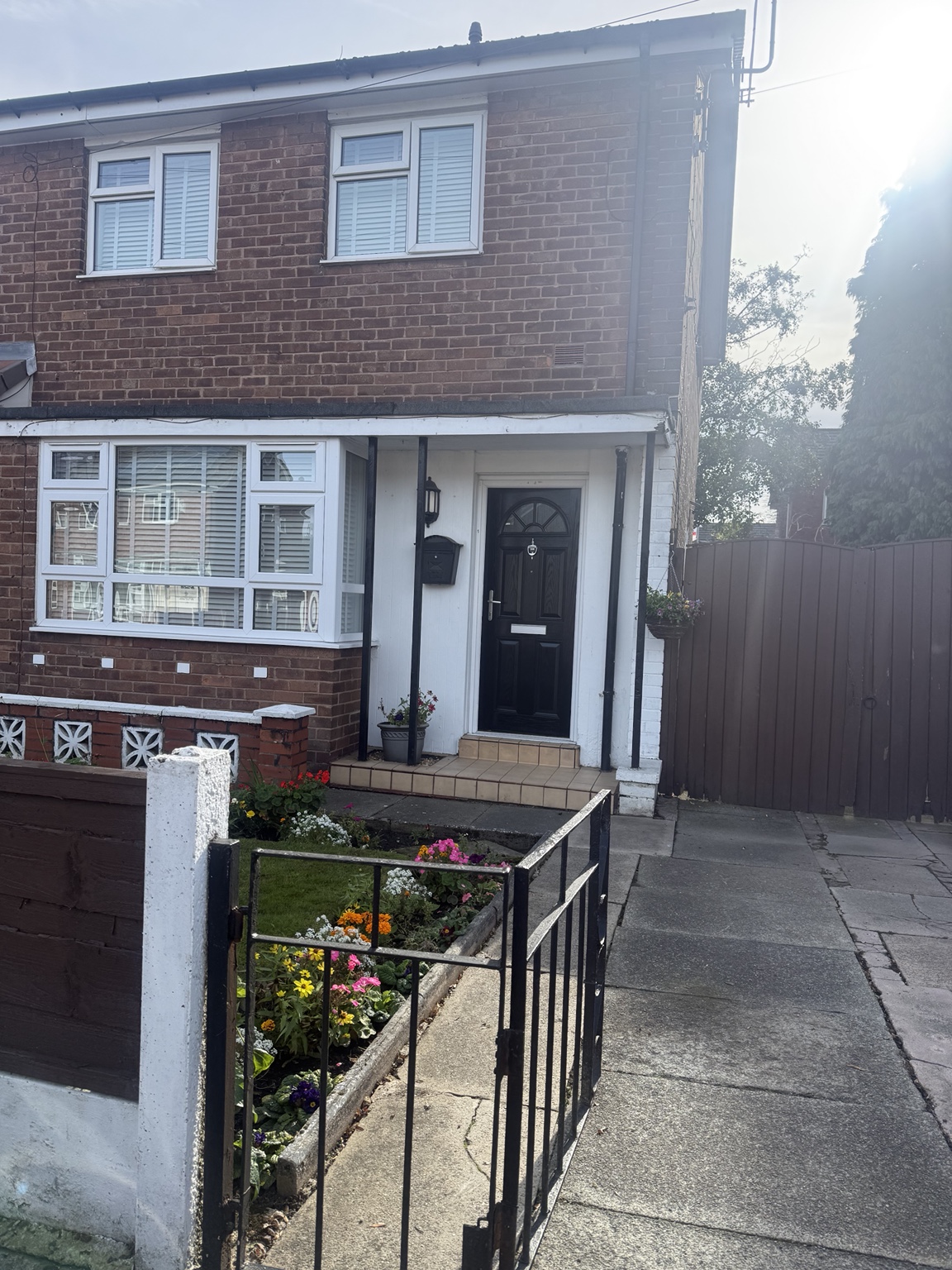 Exterior showing the finished black front door and existing white windows